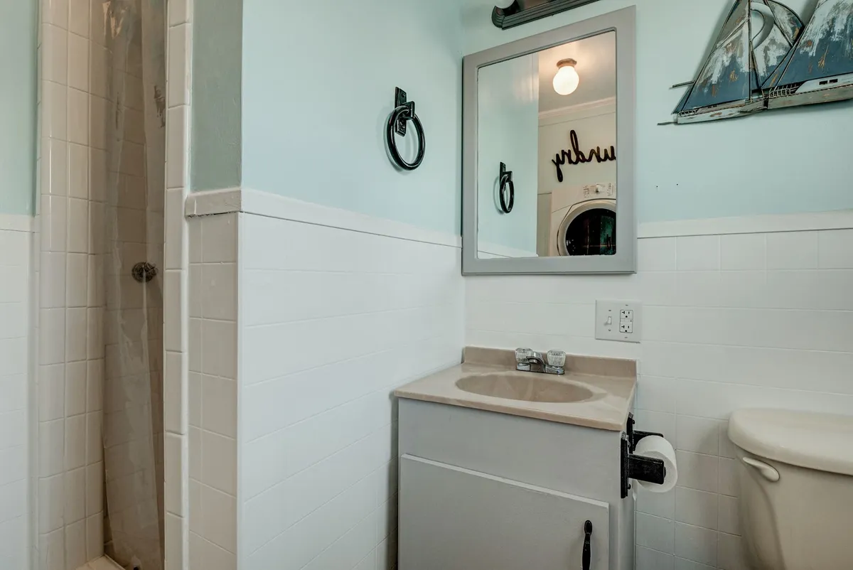 A bright, modern bathroom with a clean vanity, ample mirror, and a spacious shower area. The design is serene and functional, perfect for morning routines or winding down in the evening.
